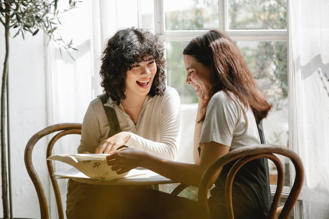 two women sitting together, smiling over paperwork