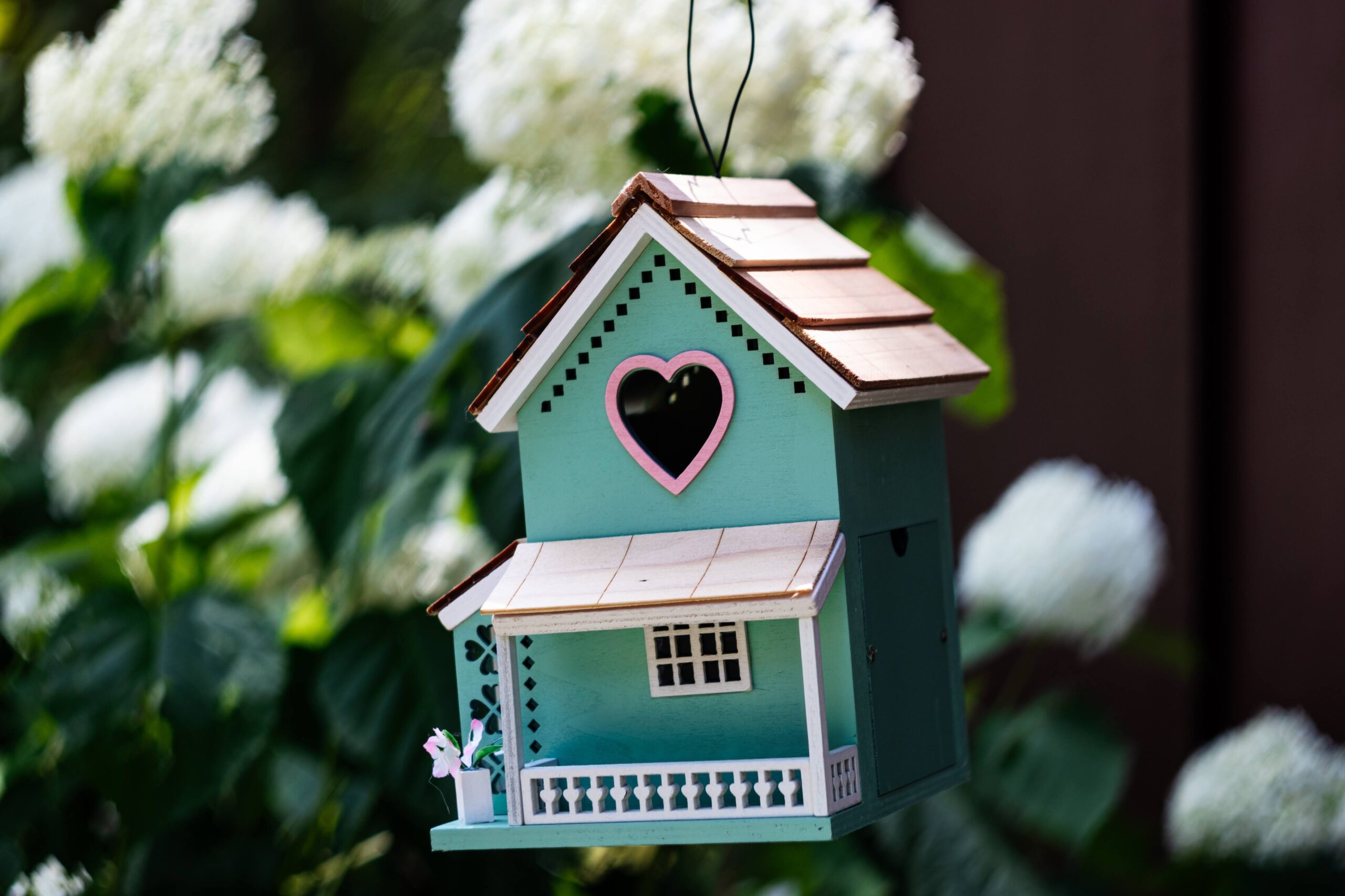 Mint-green Victorian-style birdhouse with heart-shaped hole in gable.