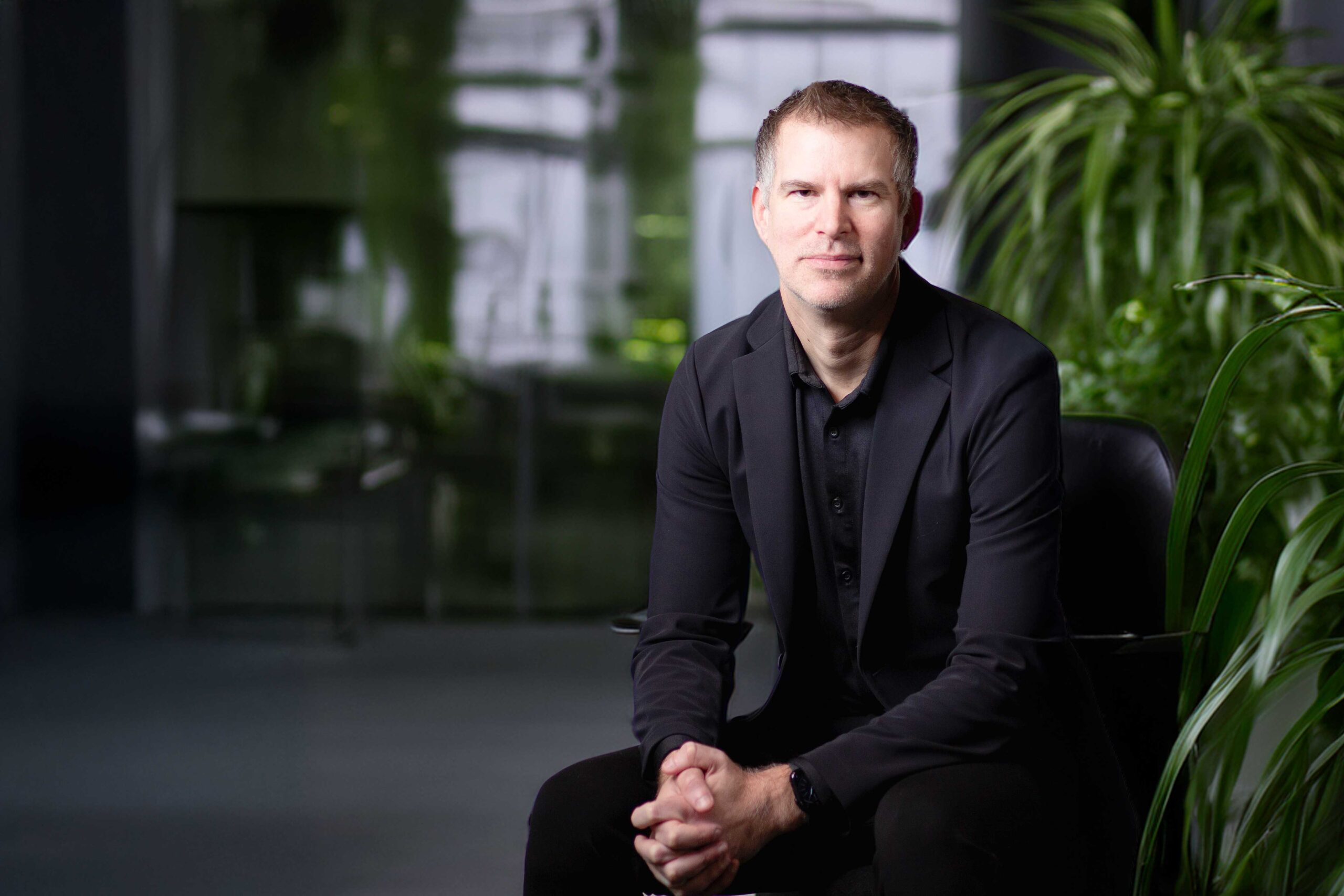 Michael Great sits in front of a plant in an office.